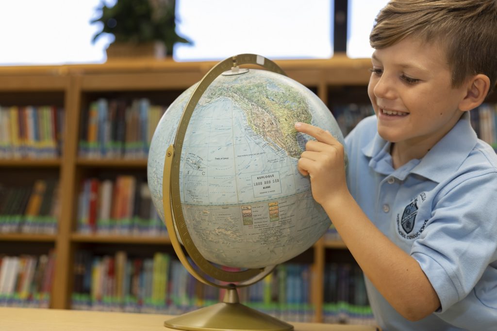 St. Cecelia student with a globe