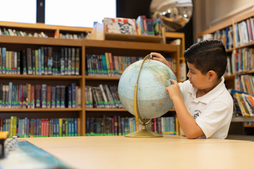 Student studying geography on a globe at St. Cecelia Interparochial Catholic School